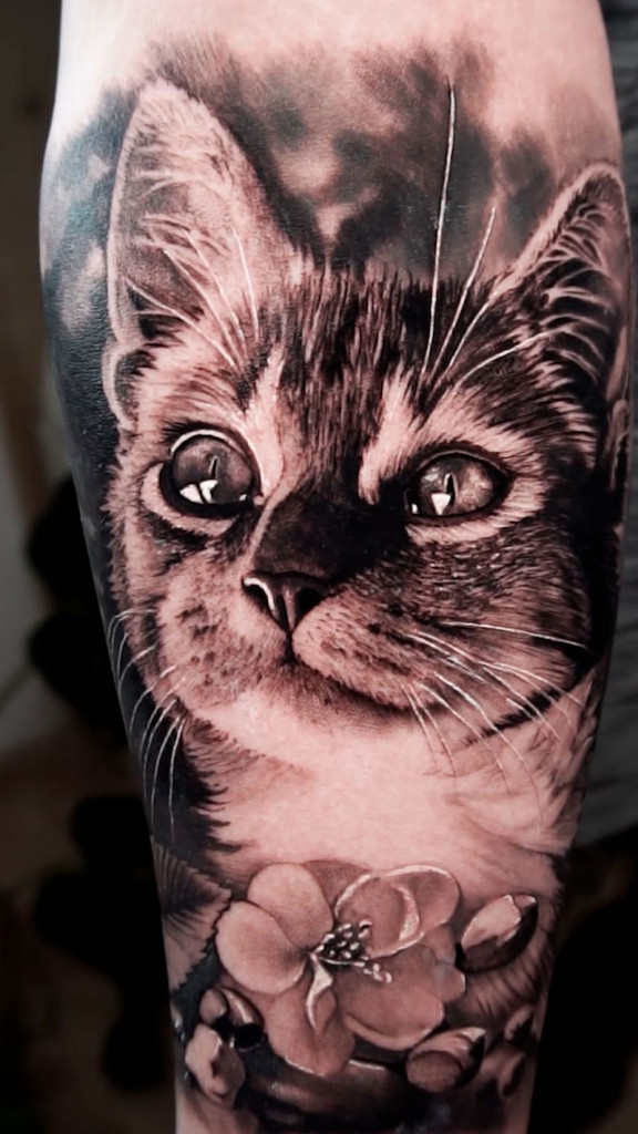 Tatouage réaliste de chat avec fleurs à Porrentruy, Suisse